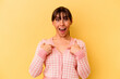 Young Argentinian woman isolated on yellow background surprised pointing with finger, smiling broadly.