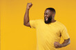 © ViDi Studio - Young exultant happy black man 20s in bright casual t-shirt doing winner gesture celebrate clenching fists say yes isolated on plain yellow color background studio portrait. People lifestyle concept.