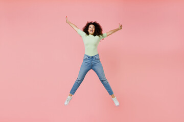 Poster - Full size body length happy excited vivid young curly latin woman 20s wear casual clothes sunglasses jumping rising hands spreading legs isolated on plain pastel light pink background studio portrait