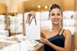 © Syda Productions - sale, luxury and people concept - smiling elegant woman in dress with small shopping bag over jewelry store background