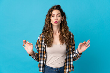 Wall Mural - Young caucasian woman isolated on blue background in zen pose