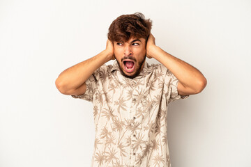 Wall Mural - Young mixed race man isolated on grey background covering ears with hands trying not to hear too loud sound.