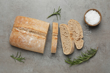 Fresh crispy ciabatta, salt and rosemary on grey table, flat lay