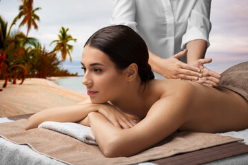 Poster - wellness, beauty and relaxation concept - beautiful young woman lying and having back massage at spa over tropical beach background in french polynesia