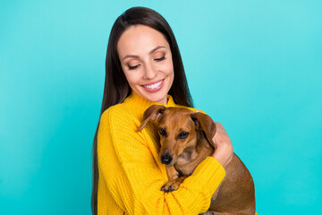 Poster - Portrait of attractive cheerful sweet careful girl owner holding in hands dog isolated over bright teal turquoise color background