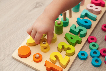 The child is playing with a colorful wooden educational toy.