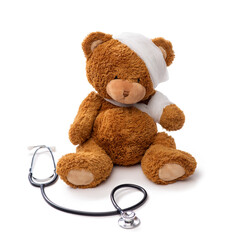 Wall Mural - medicine, healthcare and childhood concept - teddy bear toy with bandaged head and paw and stethoscope on white background