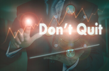 A businessman operating a computer display with a Don't Quit business word concept on it.