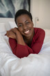 © JonoErasmus - Portrait Black African woman laying on bed, smiling looking into camera