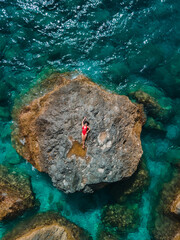 Poster - directly above woman in red swimsuit at the rock surrounded by the sea