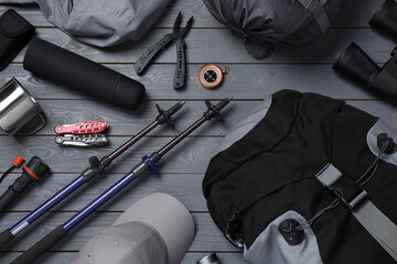 Flat lay composition with trekking poles and other hiking equipment on grey wooden background