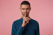 © timtimphoto - studio portrait of middle age middle eastern man wears blue checkered shirt shows silence gesture with angry facial expression, raised up eyebrow, isolated over pink background