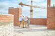 © zinkevych - Three men and woman looking at laptop at construction site