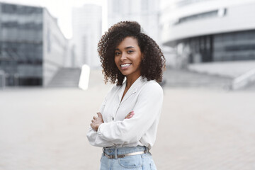 Young businesswoman in a city looking at camera, African american student girl portrait, Young woman with crossed arms smiling, People, enjoy life, student lifestyle, city life, business concept