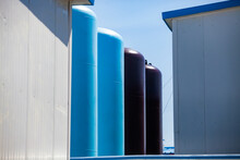 Blue And Black Tanks Of Water Purification System On Blue Sky Background. Petrochemical (oil Refining) Plant Equipment.