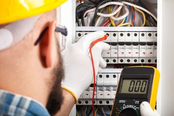 Wall Mural - Electrician at work on an electrical panel protected in safety goggles and gloves; Coronavirus. Construction industry. Covid 19 Prevention.