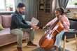 © pressmaster - Cute schoolgirl playing cello while her music teacher sitting near by and explaining how to play musical instrument