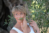 Fototapeta Na drzwi - Frau riecht an Olivenblättern in Olivenplantage