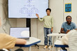 © Seventyfour - Full length portrait of smiling teenage boy giving presentation in coding class for children, copy space