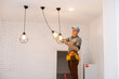 © Angelov - An electrician is installing spotlights on the ceiling