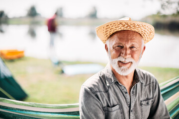 Wall Mural - happy senior man enjoys in camping and relaxes in hammock while looking at camera.