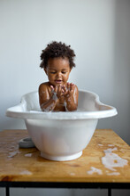 Black Toddler Sitting In Bath With Foam. Bathing Without Tears. Cute Emotional Baby Is Engaged In Hygiene Procedures, Have Fun. Disinfection, Prevention Against Diseases And Viruses