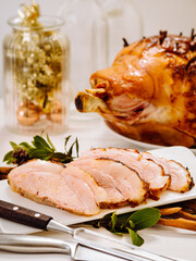 Wall Mural - Carved platter of juicy and succulent pork meat on white plate with whole glazed ham hock festive backgound. Celebrate Thanksgiving, Christmas or New Year Party Concept. Selective focus. Bright light