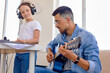 © Roman - beautiful talented caucasian little girl and pleasant father are playing guitar and piano. Performing music together in bright cozy studio. Side view. Music education and extra-curricular lessons.
