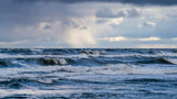 Fototapeta  - Piękny widok wzburzonego morza na tle promieni 
 słońca przebijających się przez ciężkie chmury (Morze Bałtyckie)