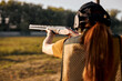 © Roman - Rear view redhead caucasian woman on tactical gun training classes. Woman with weapon. Outdoor Shooting Range. Side view on beautiful lady with rifle machine gun in the forest, slim female is hunting