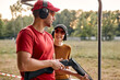 © Roman - Handsome male shooting instructor teaches the backslider how to handle weapon on training course in outdoor range. cheerful teacher and woman in protective spectacles and headset have fun, laugh