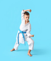 Wall Mural - Little boy practicing karate on color background