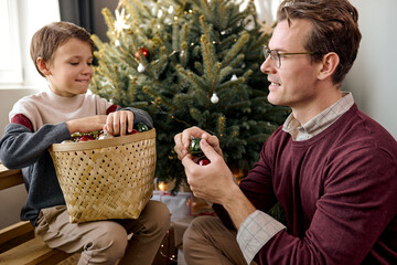 dad and son together decorating Christmas tree on the eve of holidays. family concept. Celebrating Christmas and New Year 2022, having fun, happy time together.caucasian adult man and teenage boy