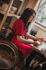 Wall Mural - Woman in a wheelchair gesturing and talking to her friend in a cafe. Accessible common areas for people with disabilities. Girls in wheelchairs on vacation while traveling.