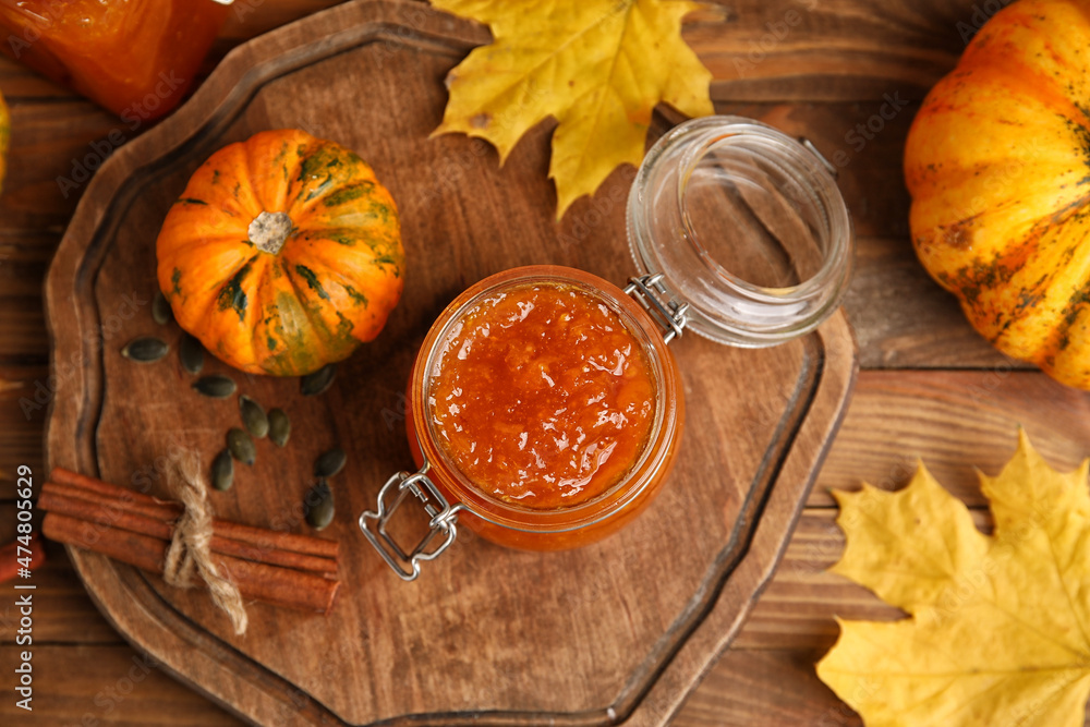 Jar of sweet pumpkin jam on wooden background