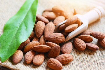 Canvas Print - Almonds on wooden scoop and sack  background top view on the table, Close up roasted almond nuts natural protein food and for snack