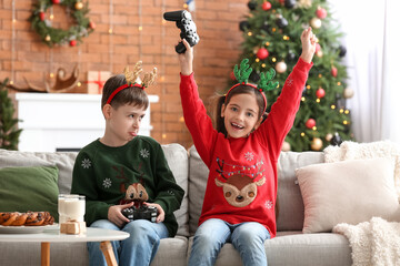 Sticker - Cute little children playing video game at home on Christmas eve