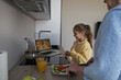 © Svitlana - Adorable child videocalling her mom and dad from grandma kitchen