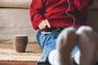© Farknot Architect - Closeup of a woman using mobile phone and earphones at home