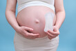 A pregnant woman holds a sanitary pad in her hands