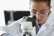 © H_Ko - Female chemist investigate sample under microscope equipment in lab
