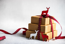 Stack Of Three Gift Boxes Tied With A Red Ribbon And Christmas Reindeer Decorations