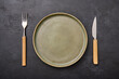 © Vitaliy - Empty green plate with fork and knife on black graphite background. Top view design concept, copy space