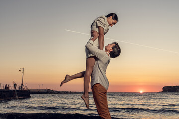 Wall Mural - Photoshoot of young helthy beautiful couple, boy and girl, dating at the beach - Man and woman lovers dancing near the ocean in a sunny day looking at each others