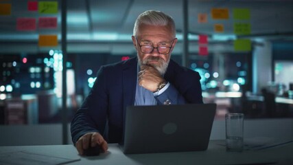 Wall Mural - Successful Senior Businessman Working on Laptop Computer in Big City Office Late in the Evening. Investment Analyst Checking Financial Graphs from Project Management Reports. Arc Shot.