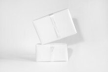 Two Gift Boxes In White Wrapping Paper With White Rope On White Table. Isolated Wrapped Gift Mock Up With Ribbon.