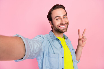 Wall Mural - Photo of young cheerful guy shoot selfie record video show fingers peace cool v-symbol isolated over pink color background