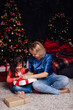 © dmitriisimakov - little curly girl and mother at the Christmas tree with gifts new year lights garland