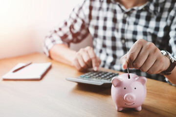 Wall Mural - image of man hand putting coins in pink piggy bank for account save money. Planning step up, saving money for future plan, retirement fund. Business investment-finance accounting concept.