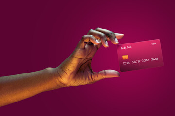 Close up african american female hand hold levitating mockup Bank credit card with online service on magenta background